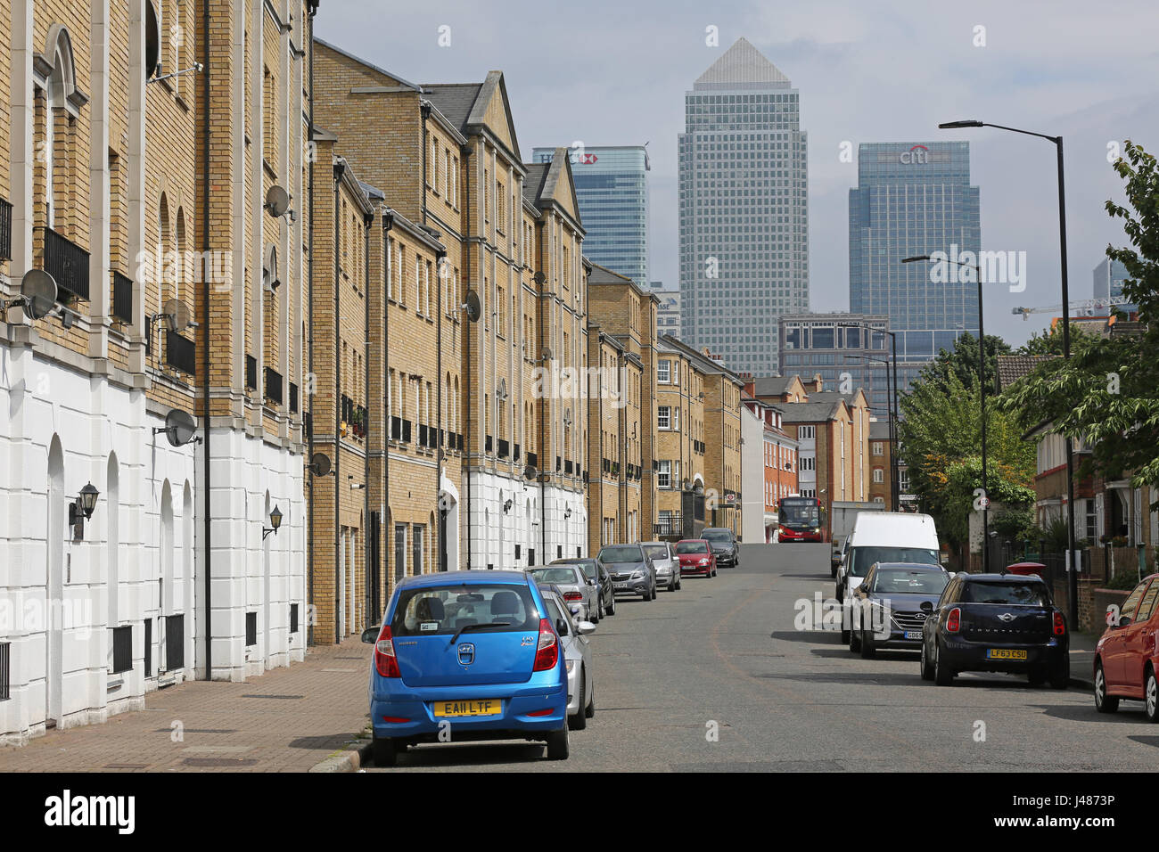 View along Rotherhithe Street in Southeast London, a residential street with the towers of Canary Wharf in the background. Shows single decker bus. Stock Photo