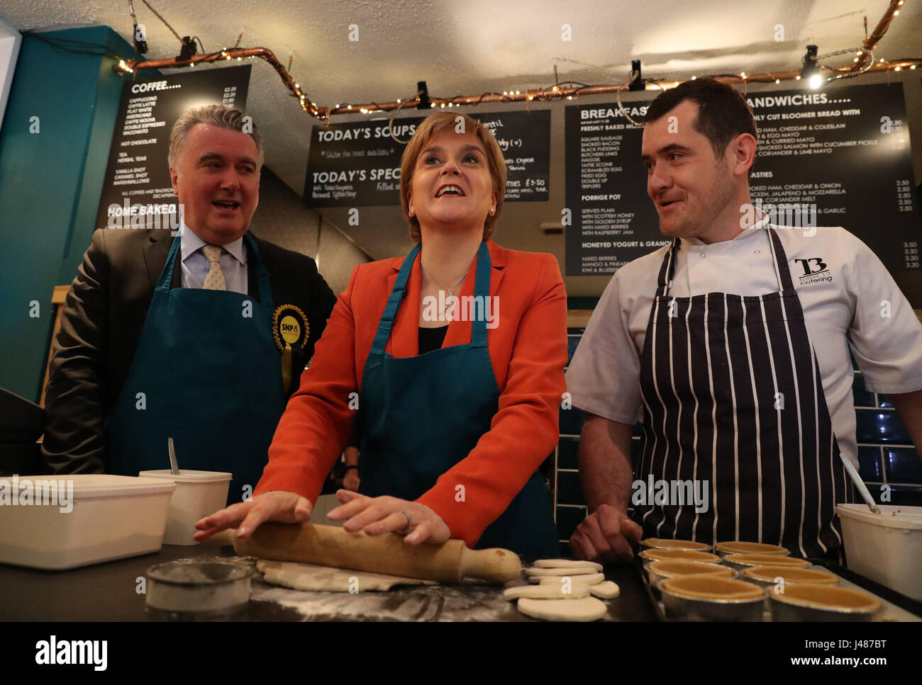 SNP Leader Nicola Sturgeon and the party's local candidate John Nicolson (left) making haggis pies with Table 13 Express co-owner Iain Murphy on a campaign visit to the cafe in Kirkintilloch, East Dunbartonshire. Stock Photo