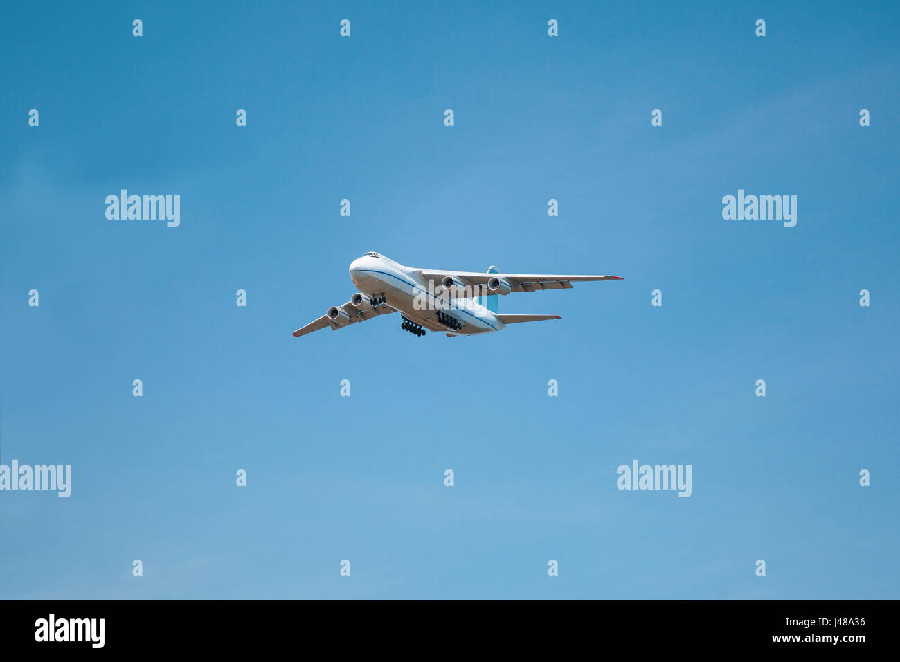 A white airplane is flying in a clear pale blue sky Stock Photo - Alamy