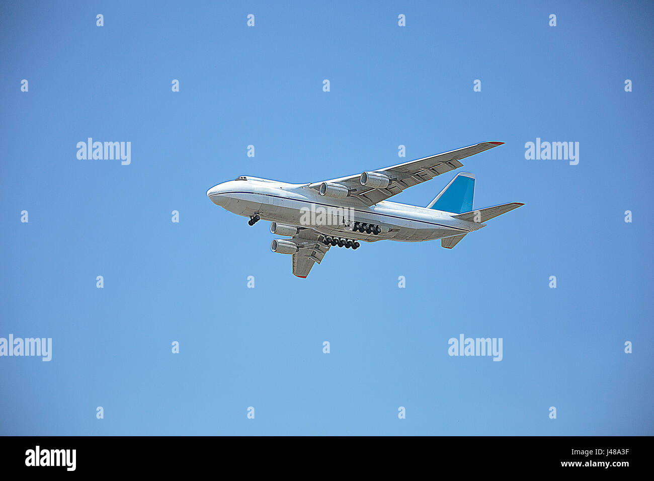 A white airplane is flying in a clear pale blue sky Stock Photo - Alamy