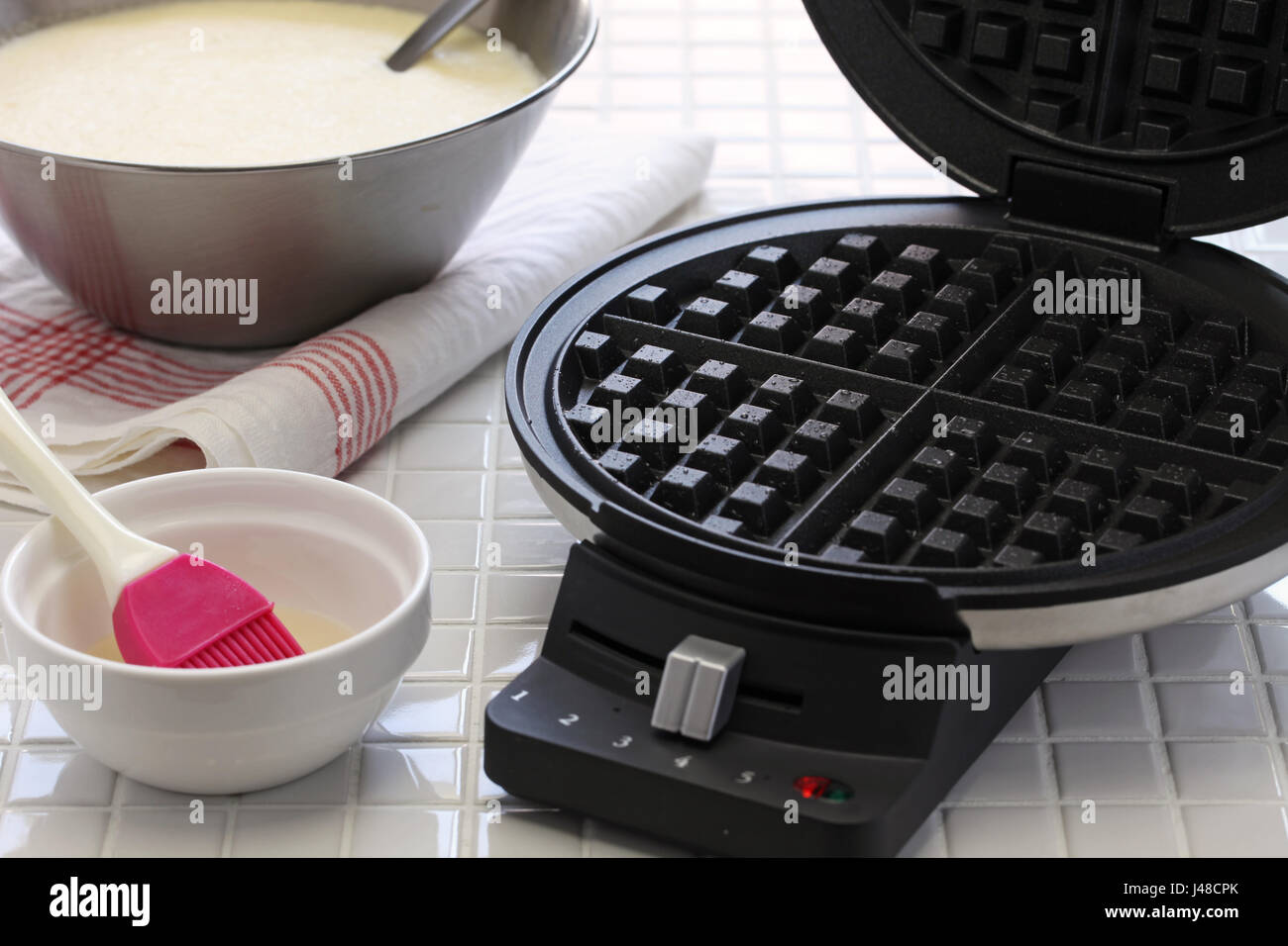 preparing homemade waffles by waffle maker machine. Stock Photo