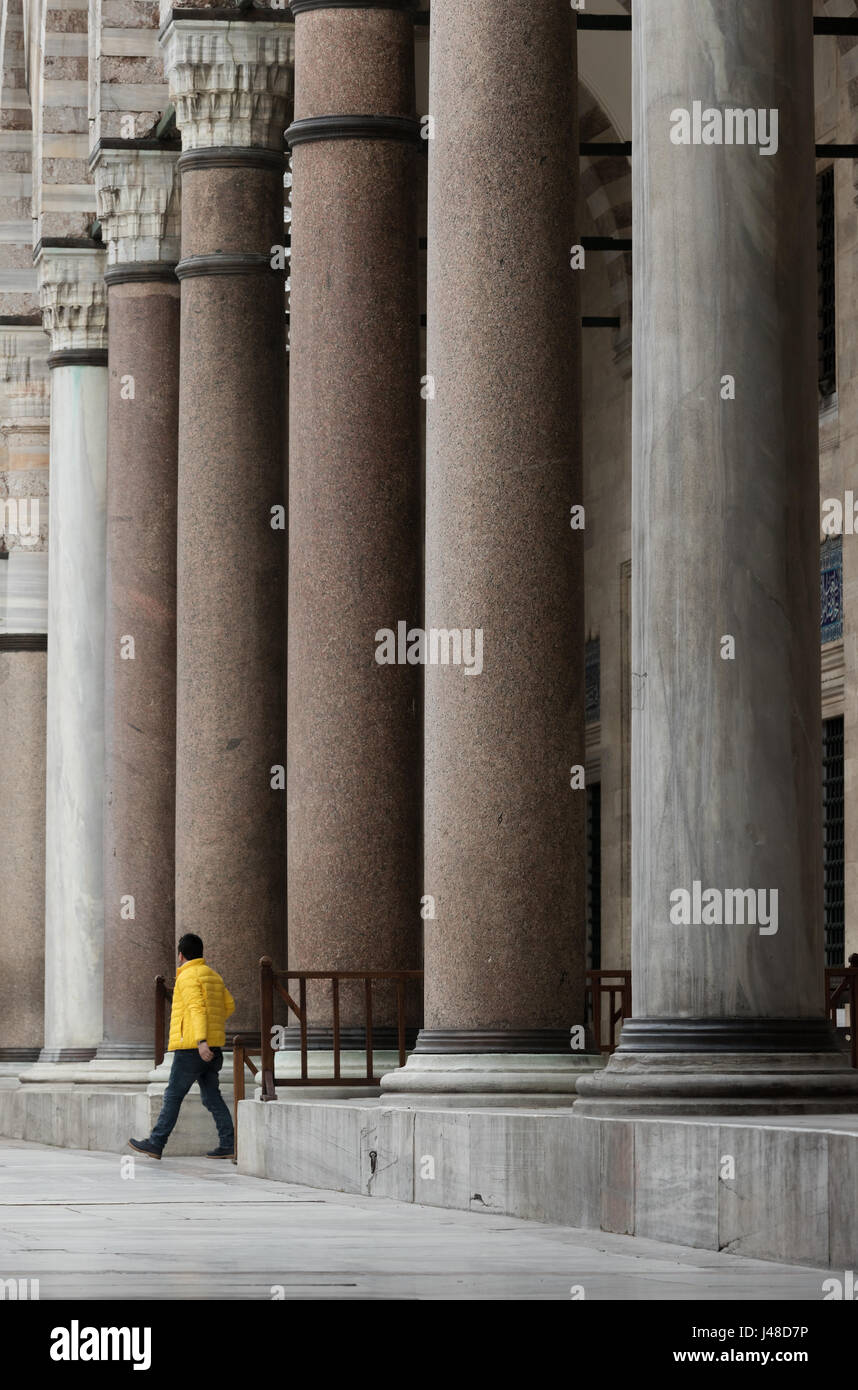 The man with yellow coat walks among the columns .. ( Courtyard of Suleymaniye Mosque mosque ) Stock Photo