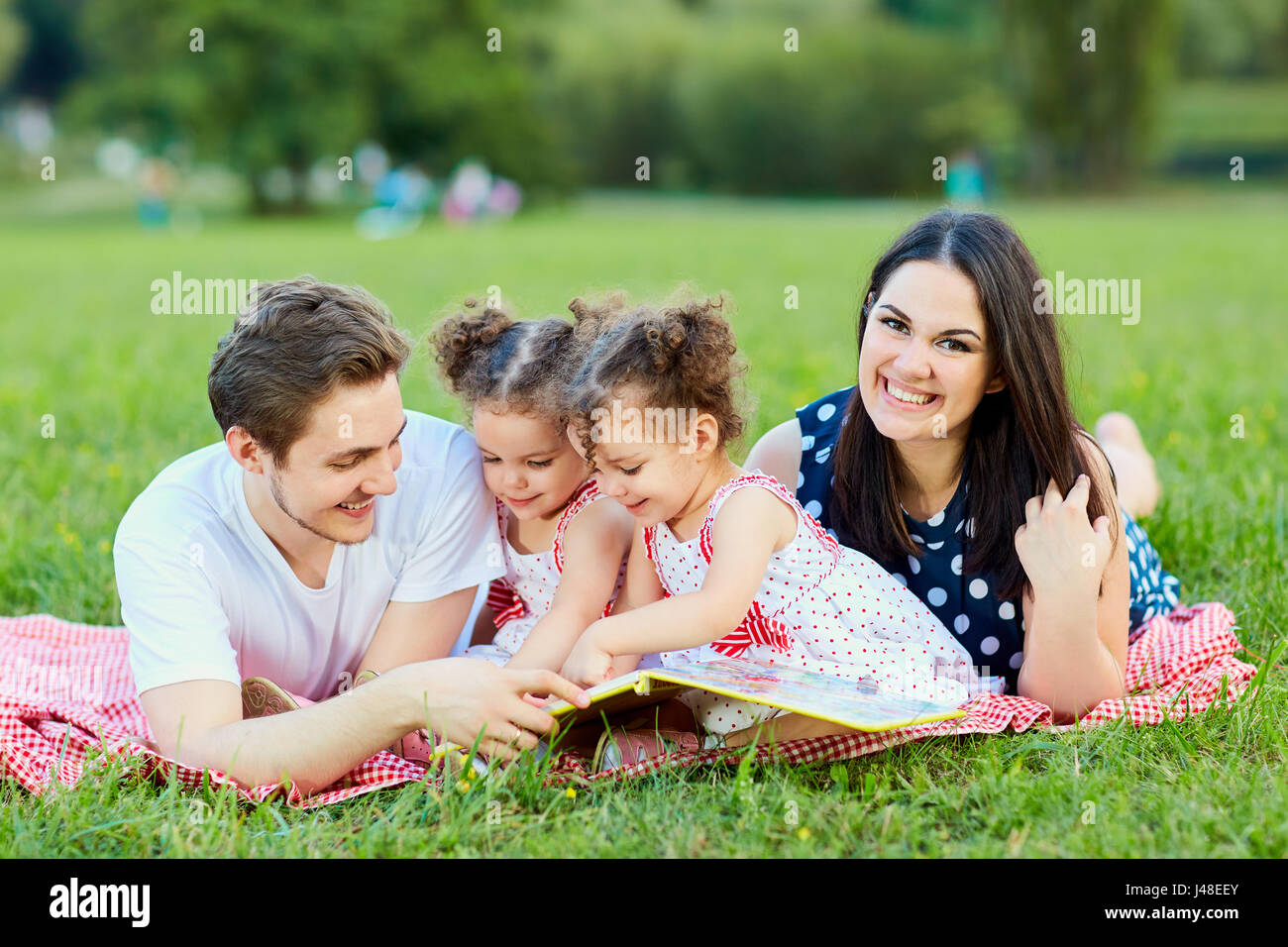 A happy family is reading book in the park Stock Photo