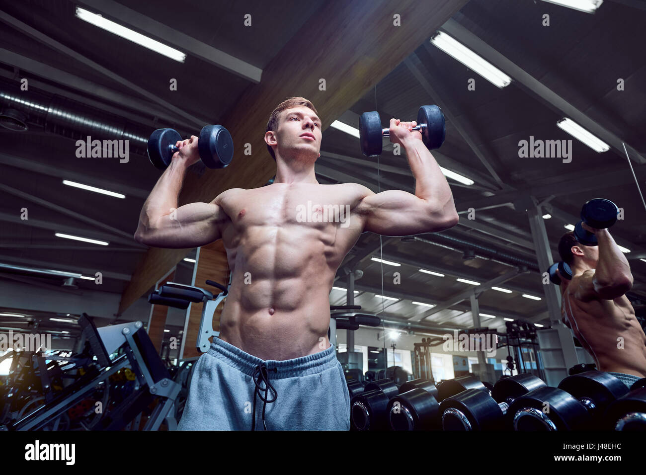 Man with a sports figure with dumbbells in the gym Stock Photo Alamy