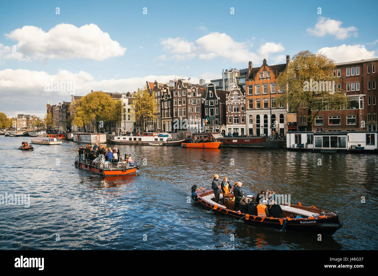 Amsterdam, Netherlands - 25 April, 2017: Local people and tourists dressed in orange clothes ride on boats and participate in celebrating King's Day Stock Photo