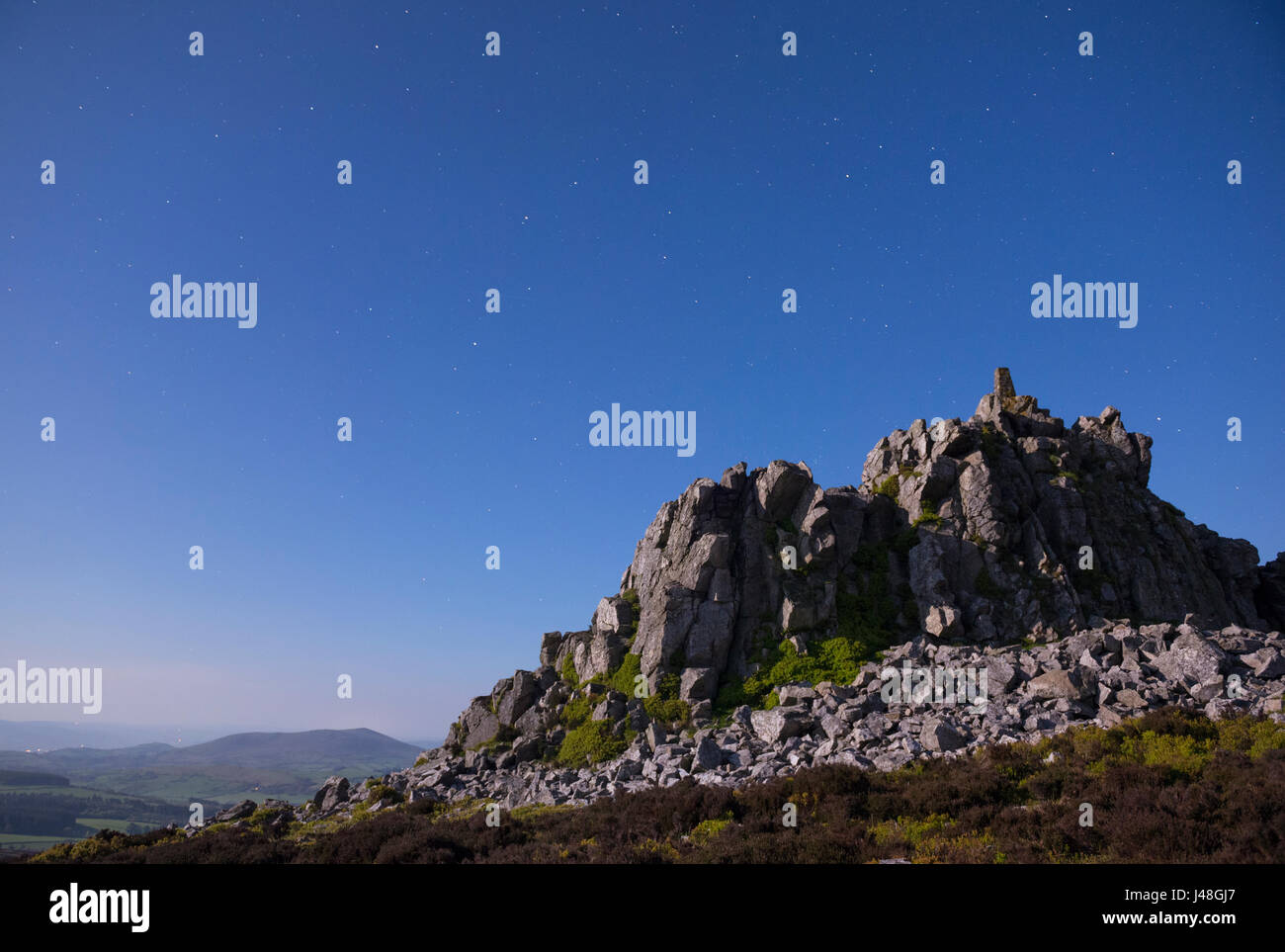 Manstone Rock on the Stiperstones, Shropshire, illuminated by moonlight, with Corndon Hill, Powys. Stock Photo