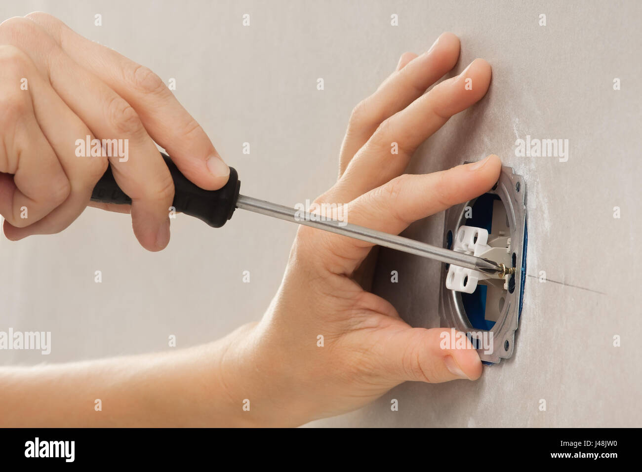 hands installing light switch with screwdriver in plasterboard wall Stock Photo
