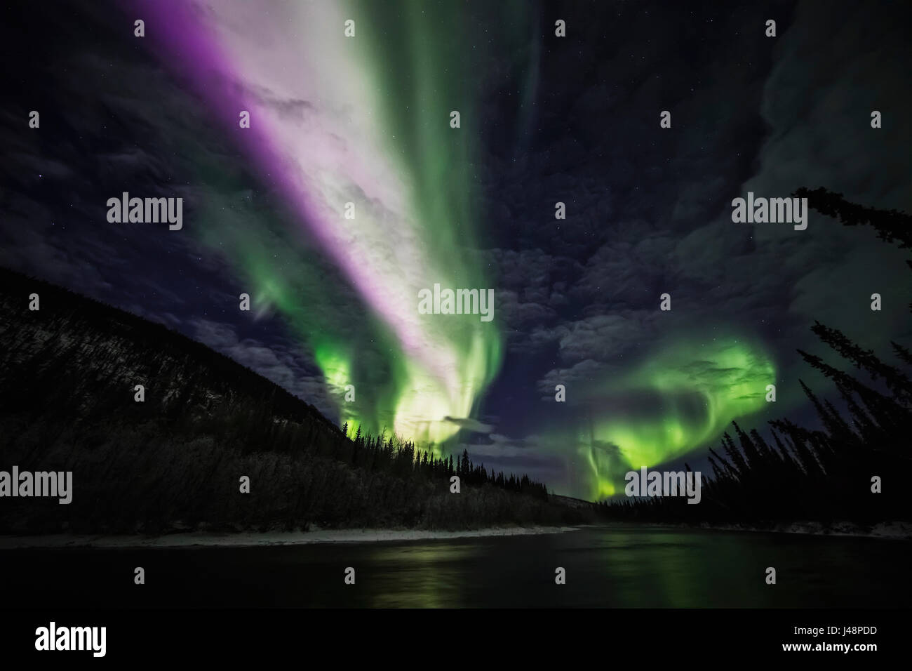 Colourful northern lights glowing in the night sky above a lake and ...