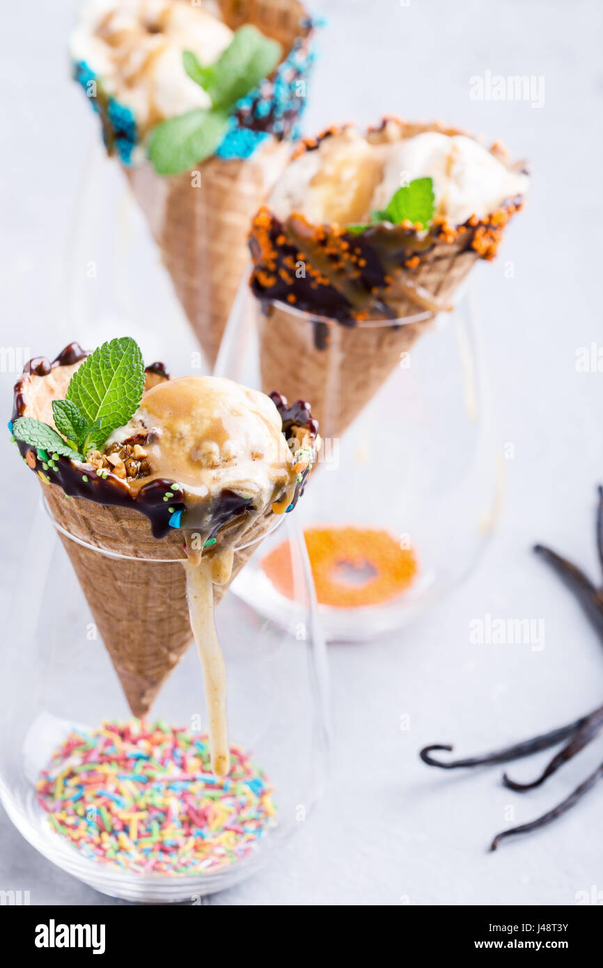 Vanilla ice cream with caramel sauce in waffle cone decorated with dark ...