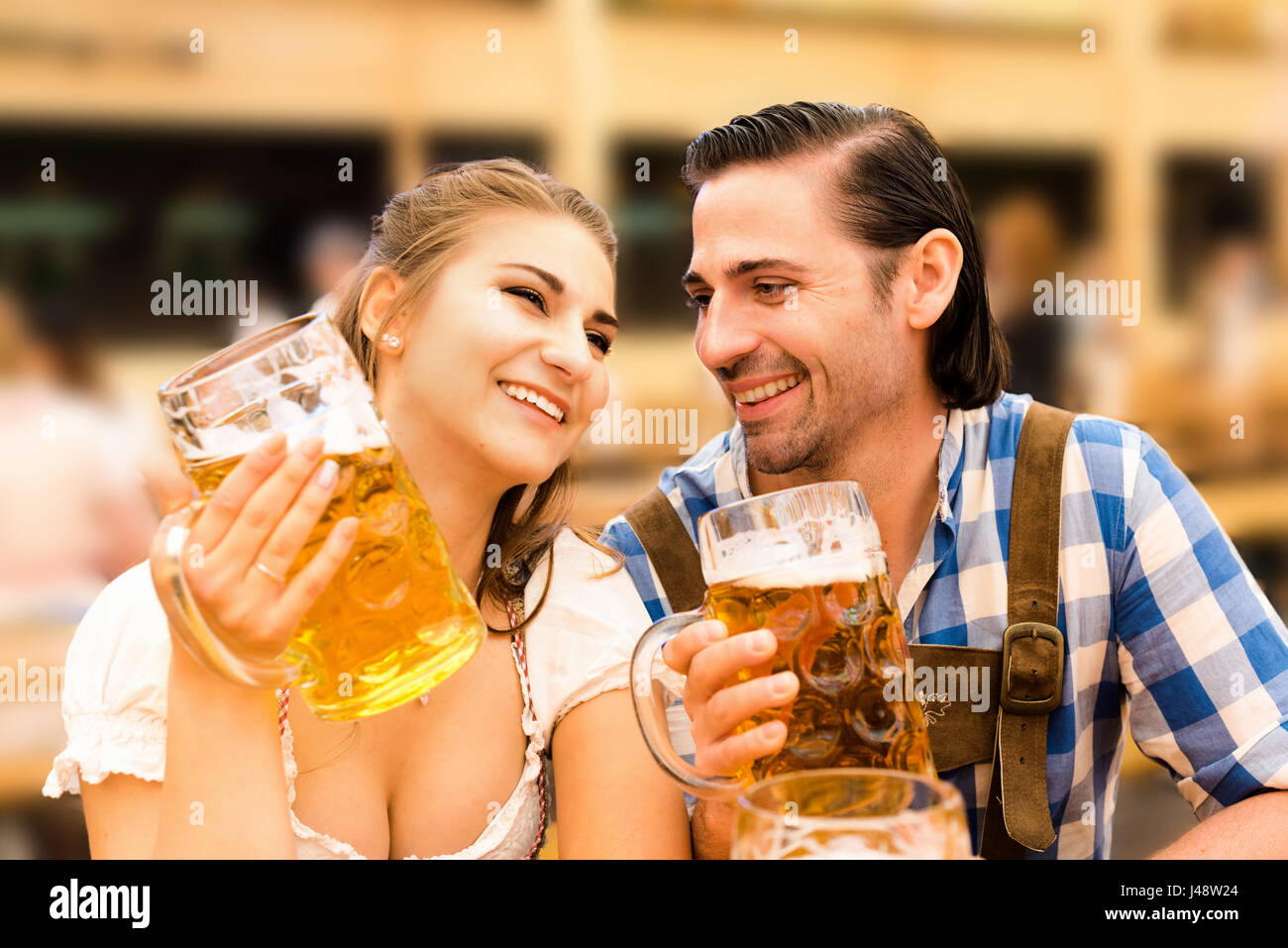 Young couple flirting in Oktoberfest beer tent while drinking beer Stock Photo