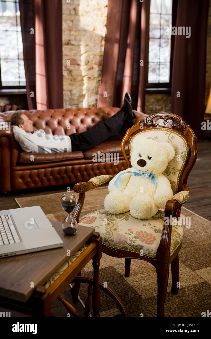 Psychology concept. Teddy bear is represented in person of psychiatrist and listening to his patient lying on sofa or couch at office. Stock Photo