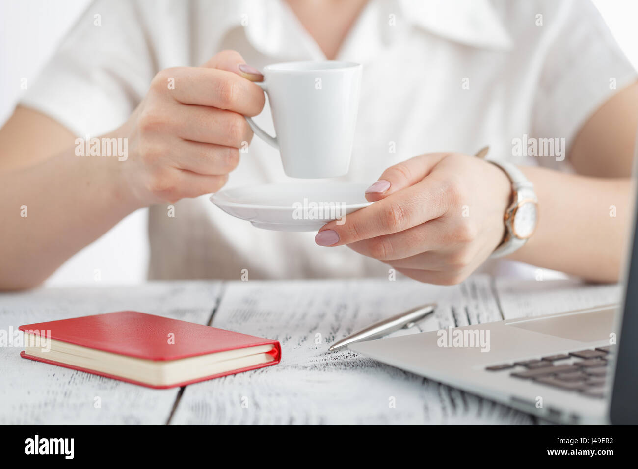 Female designer hands holding cup of hot beverage and working with ...