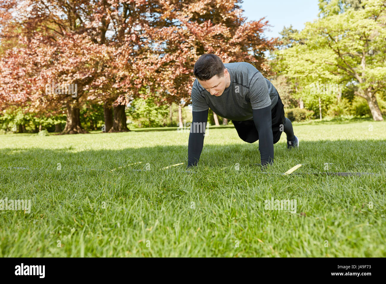 Man makes push ups at the park in summer as bodybulding exercise Stock ...