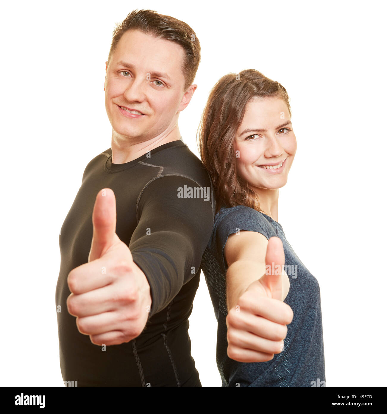 Two fitness trainers holding thumbs up together as successful couple Stock Photo