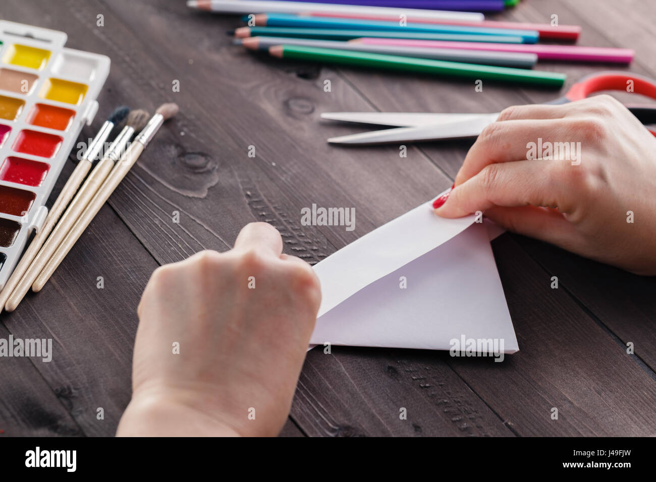 Woman do origami, bend paper sheet for do figure Stock Photo