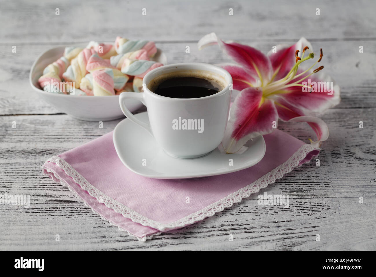 Sweets with coffee and lily flower on table Stock Photo