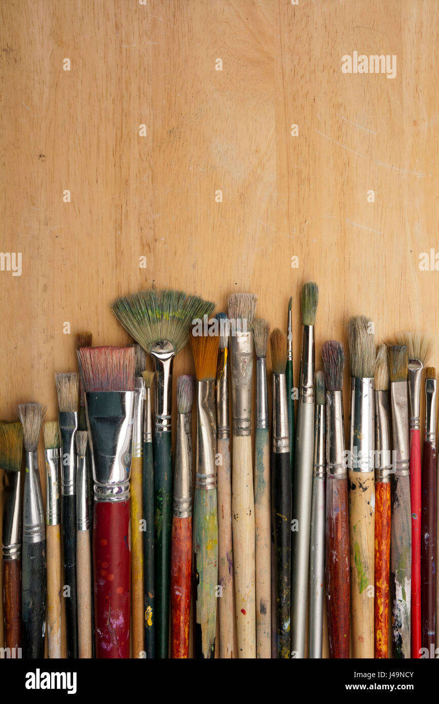 A collection of well used art paint brushes on wood Stock Photo