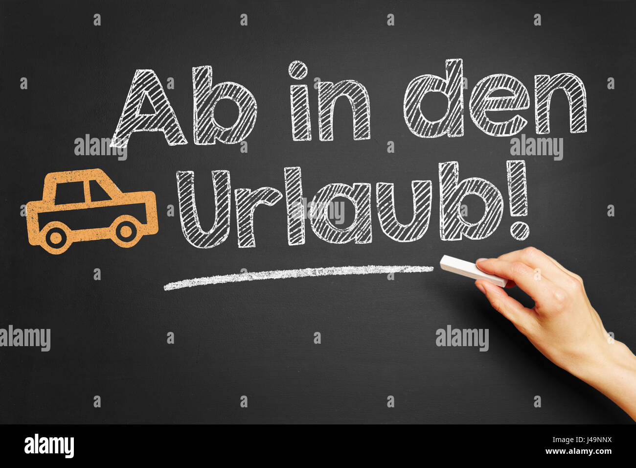 German slogan 'Ab in den Urlaub' (let's go on vacation) with chalk on blackboard Stock Photo