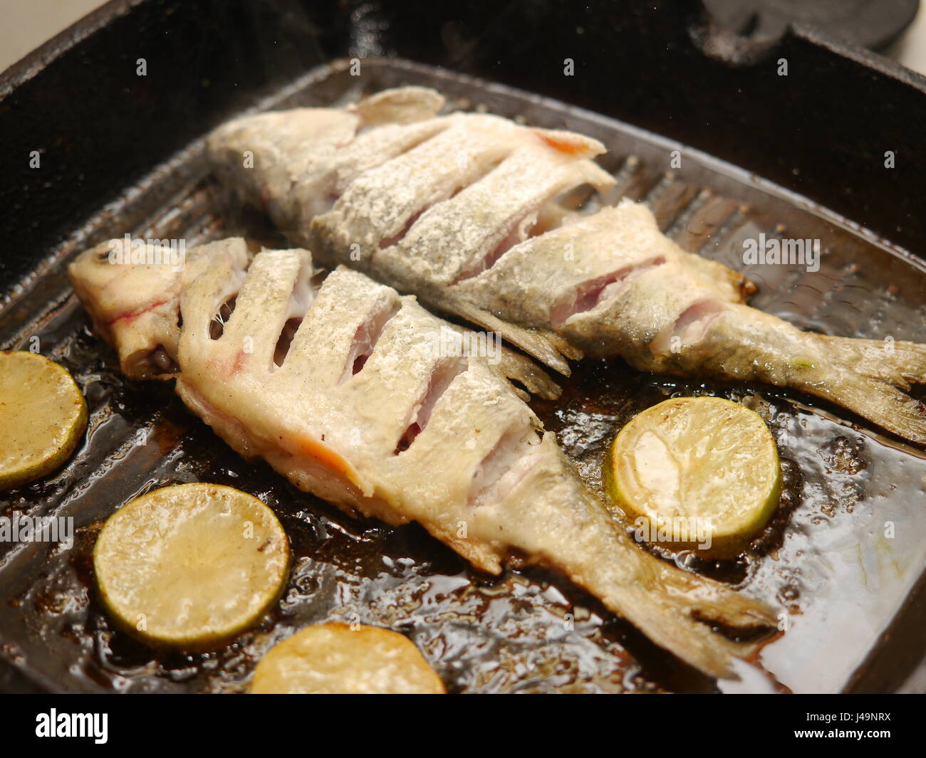 frying cut fish in a pan with lemon Stock Photo