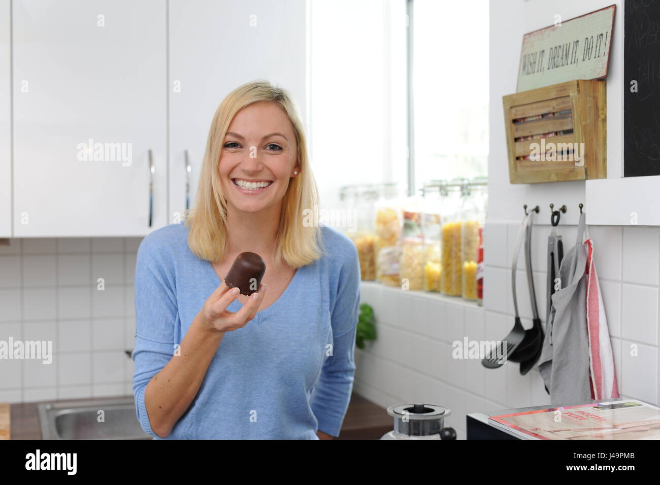 young woman eating sweets in the kitchen Stock Photo