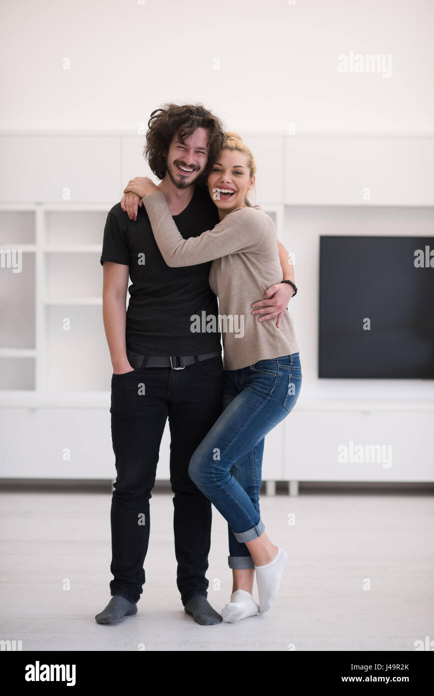 Portrait of a happy young beautiful couple hugging in their new home ...