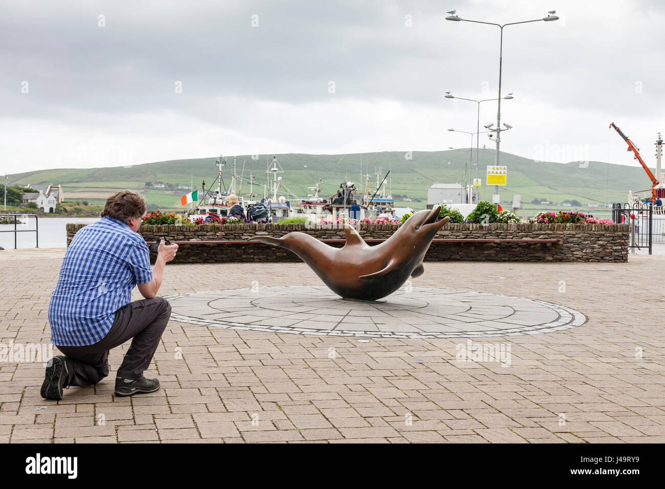 Dingle, County Kerry, Ireland - A tourist photographing the statue of Fungie the dolphin in the town of Dingle. Stock Photo