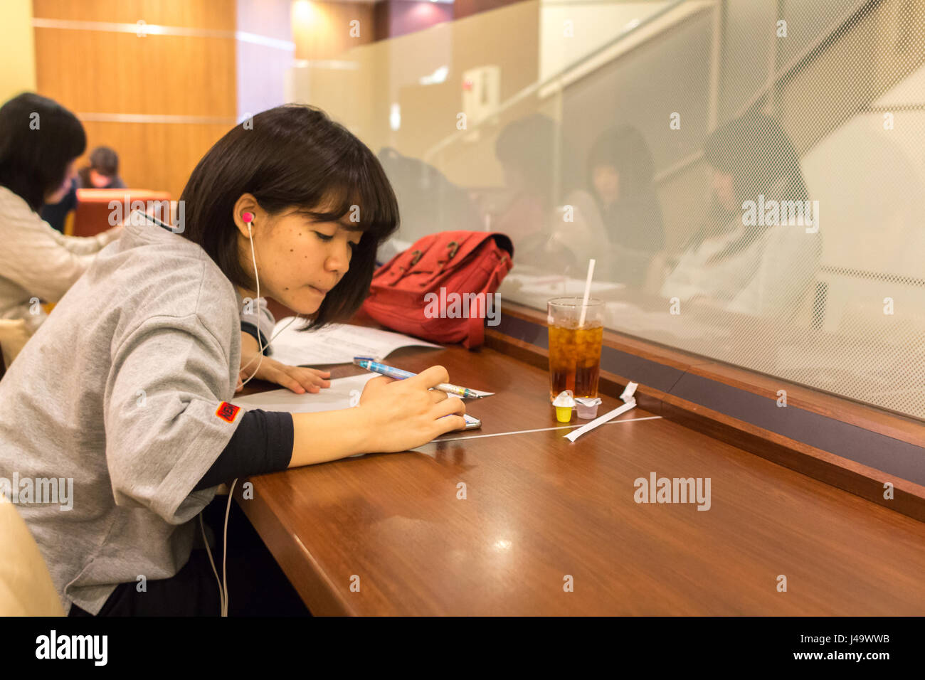 Nagasaki, Japan - March 26th, 2017: Japanese girl writing and listening music sitting inside a coffee shop in Nagasaki. Stock Photo