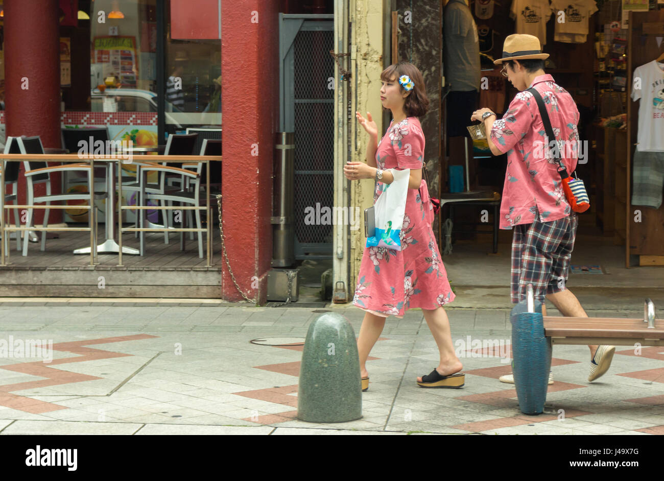 Okinawa, Japan - March 24th, 2017: A japanese couple wearing matching outfits walking on the sidewalk in Naha, Okinawa. Stock Photo