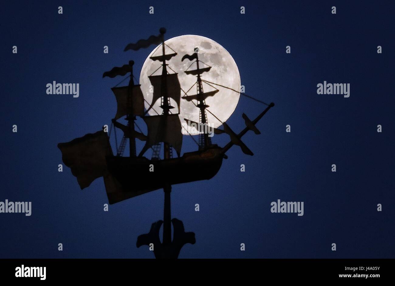 A full Moon, known as a Flower Moon in the month of May, rises behind the gilt ship weathervane above George Watson's College, Edinburgh. Stock Photo