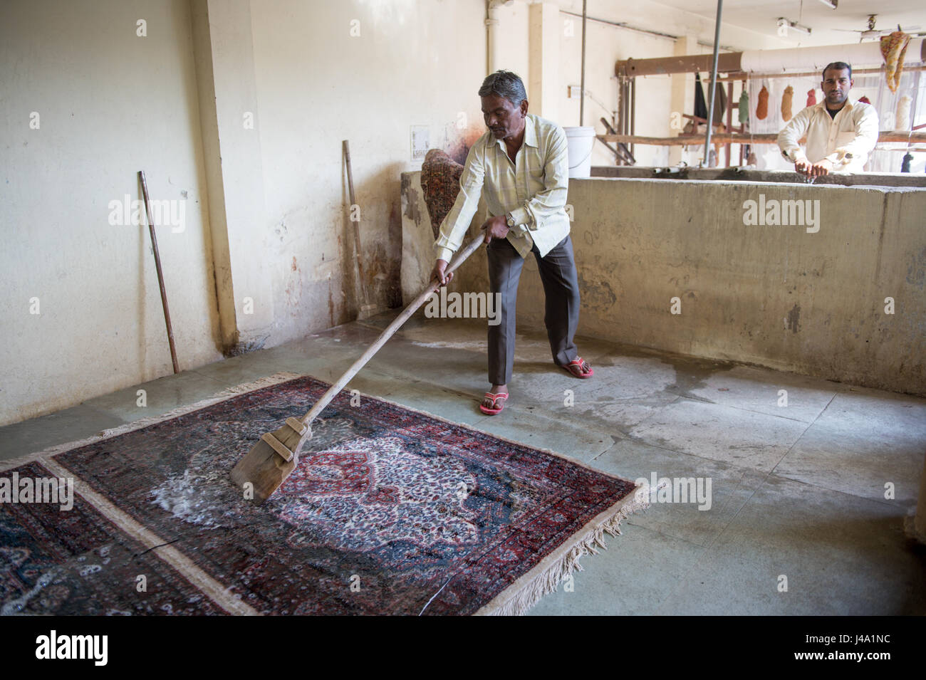 Jaipur, India Indian man cleaning off oriental rug Stock Photo Alamy