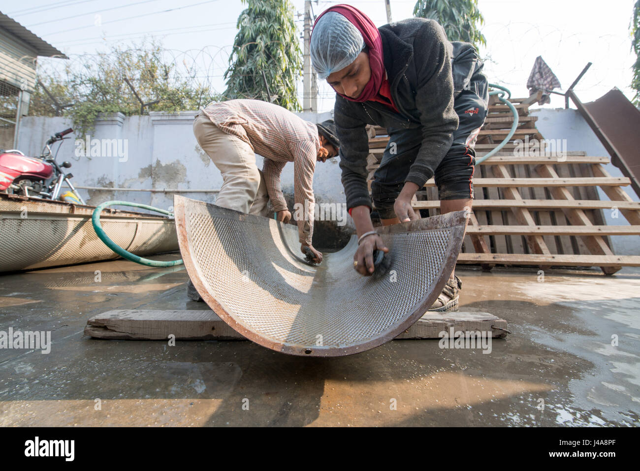 Men cleaning a rice sorting screen in New Delhi, India Stock Photo - Alamy
