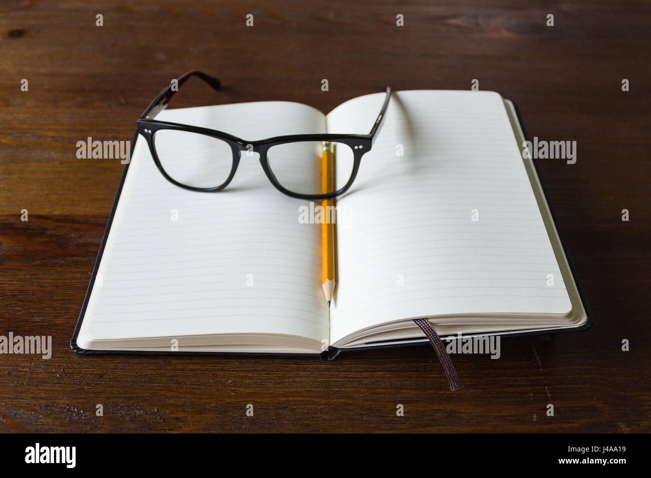 An empty notebook with pencil and a pair of glasses Stock Photo