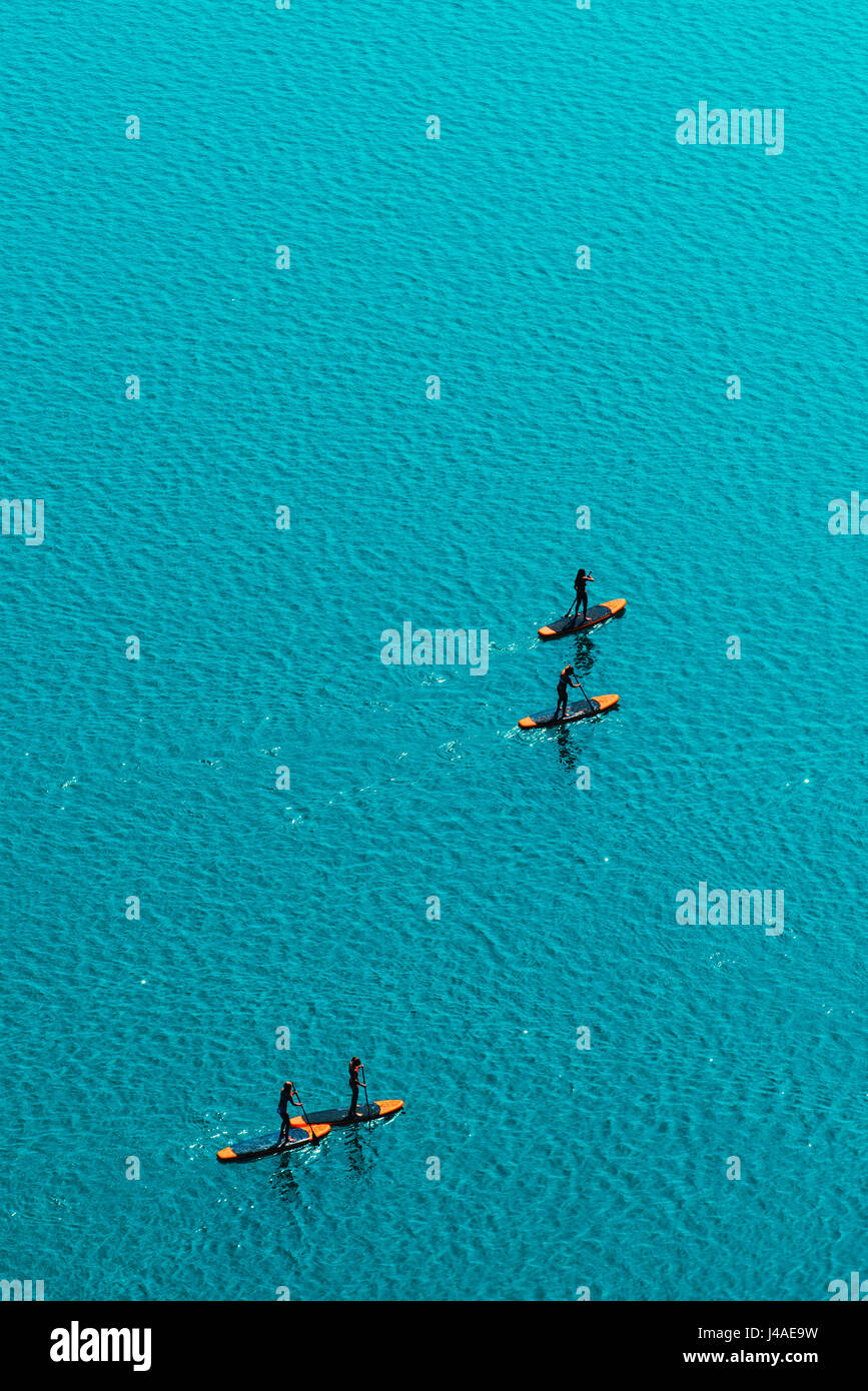 Aerial view of unrecognizable group of people stand up paddle boarding on water surface for sport, fun, leisure or recreational pursuit. Enjoying summ Stock Photo