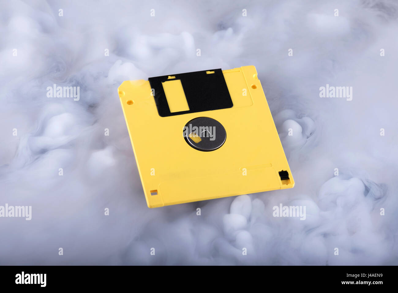 Yellow retro floppy disk in clouds. Information cloud conceptual image Stock Photo
