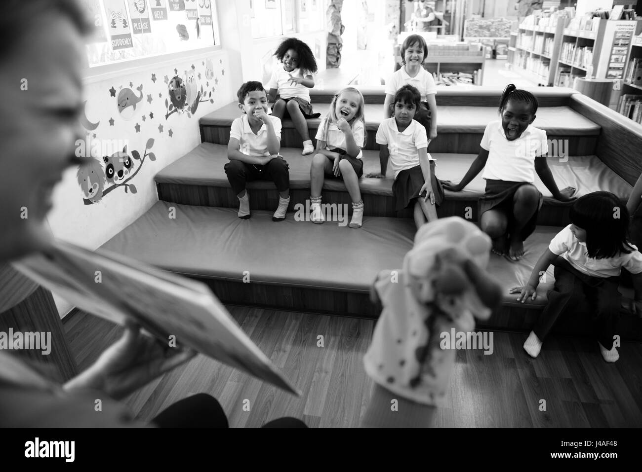 Kindergarten students sitting on the floor listening to story telling Stock Photo