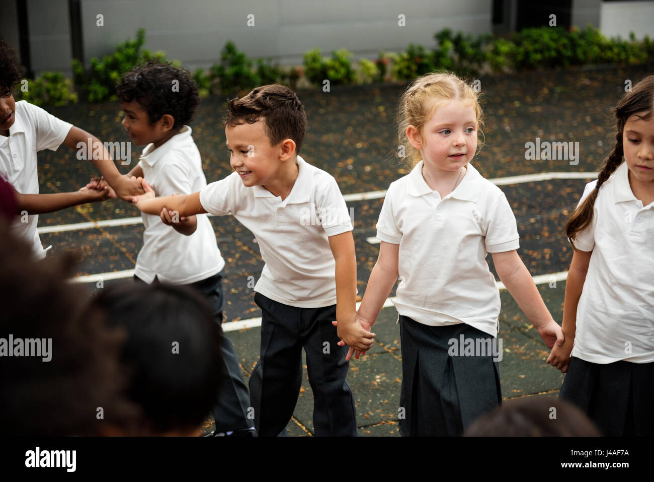 Group of diverse kindergarten students standing holding hands together ...