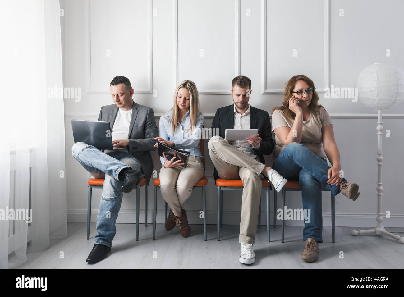 Group of young creative people sitting on chairs in waiting room Stock Photo
