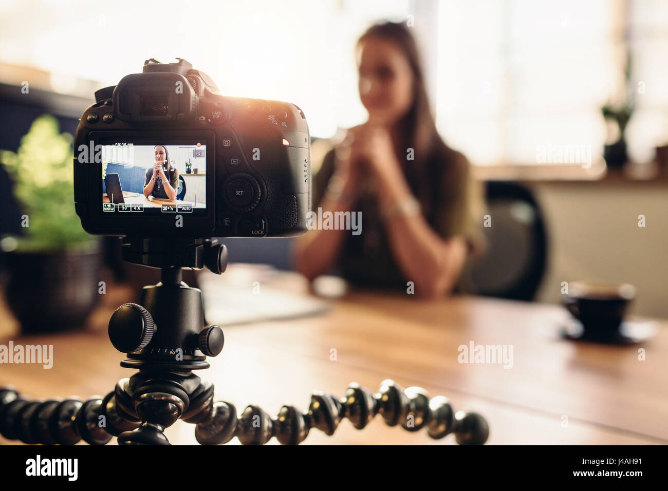 Female vlogger recording content for her video blog. Young woman in focus on digital camera screen. Stock Photo