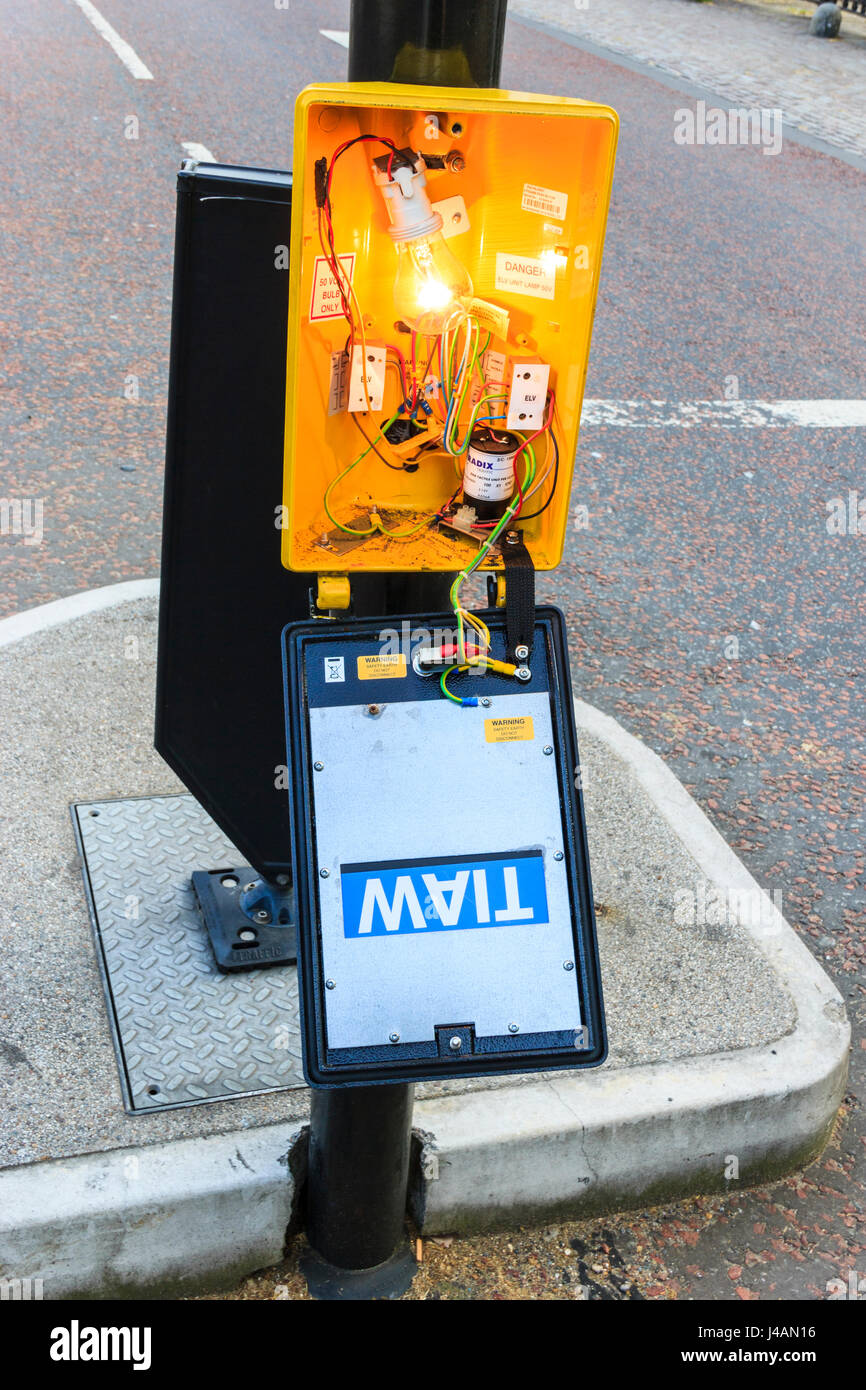 Close-up of a lamp illuminating the yellow or orange plastic housing of a  broken control panel on a pedestrian pelican crossing, London, UK Stock Photo