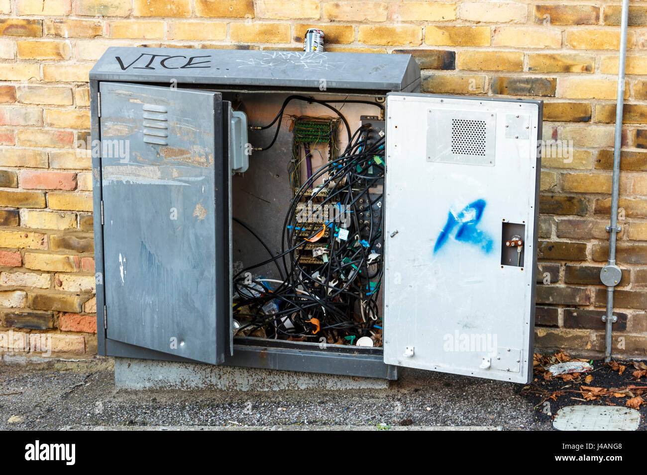 A roadside telecoms box with the door open, showing a tangle of wires and cables inside, London, UK Stock Photo
