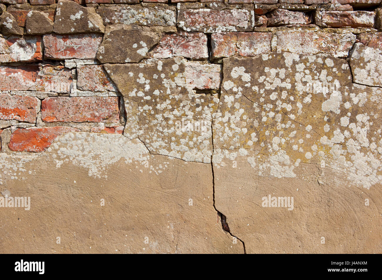 background image of an old weathered brick wall with cracked cement rendering Stock Photo