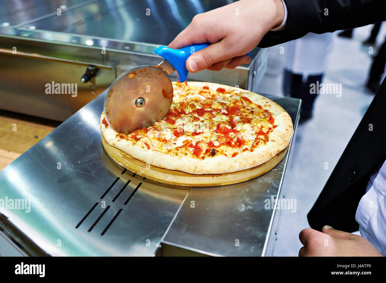 Man in a suit cuts a pizza Stock Photo