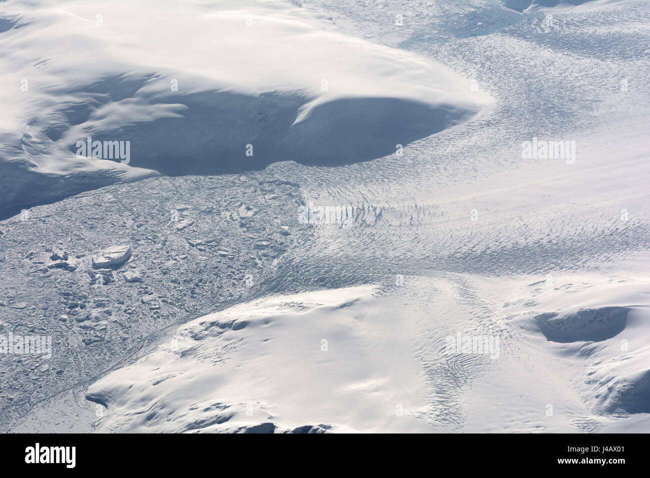 Snout of glacier in East Greenland calving into ice-chocked fjord and creating icebergss Stock Photo