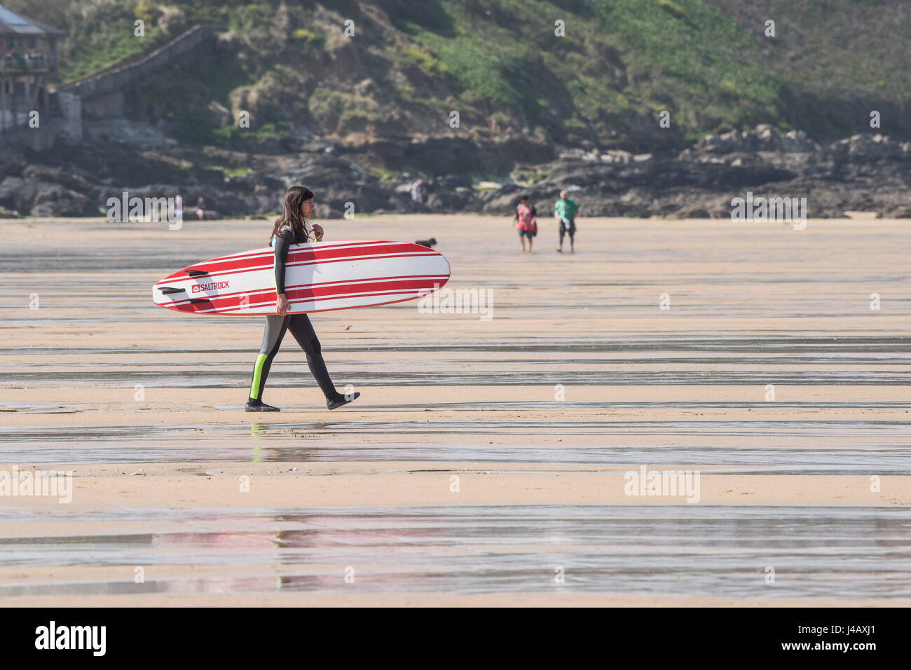 A female surfer carrying her surfboard Fistral Beach Newquay Cornwall