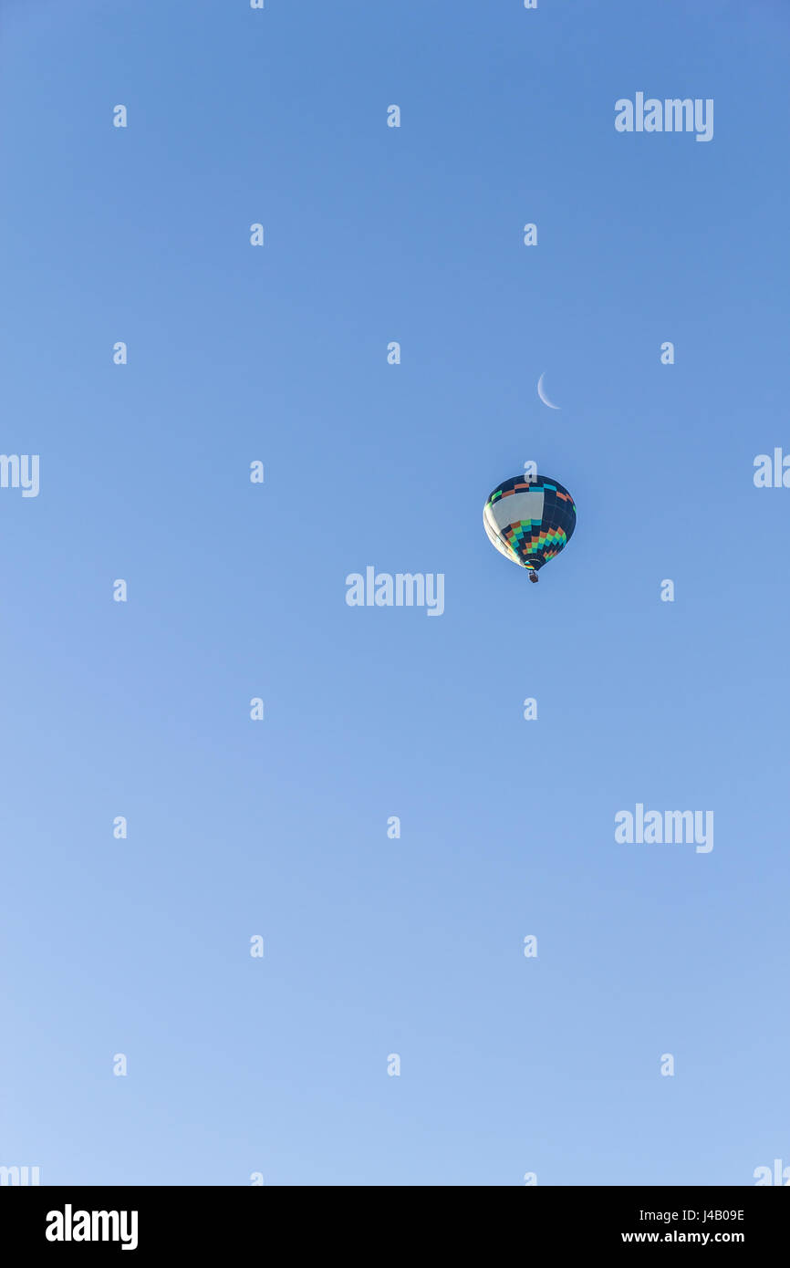 Colored hot air balloon flying in a blue sky and moon Stock Photo - Alamy