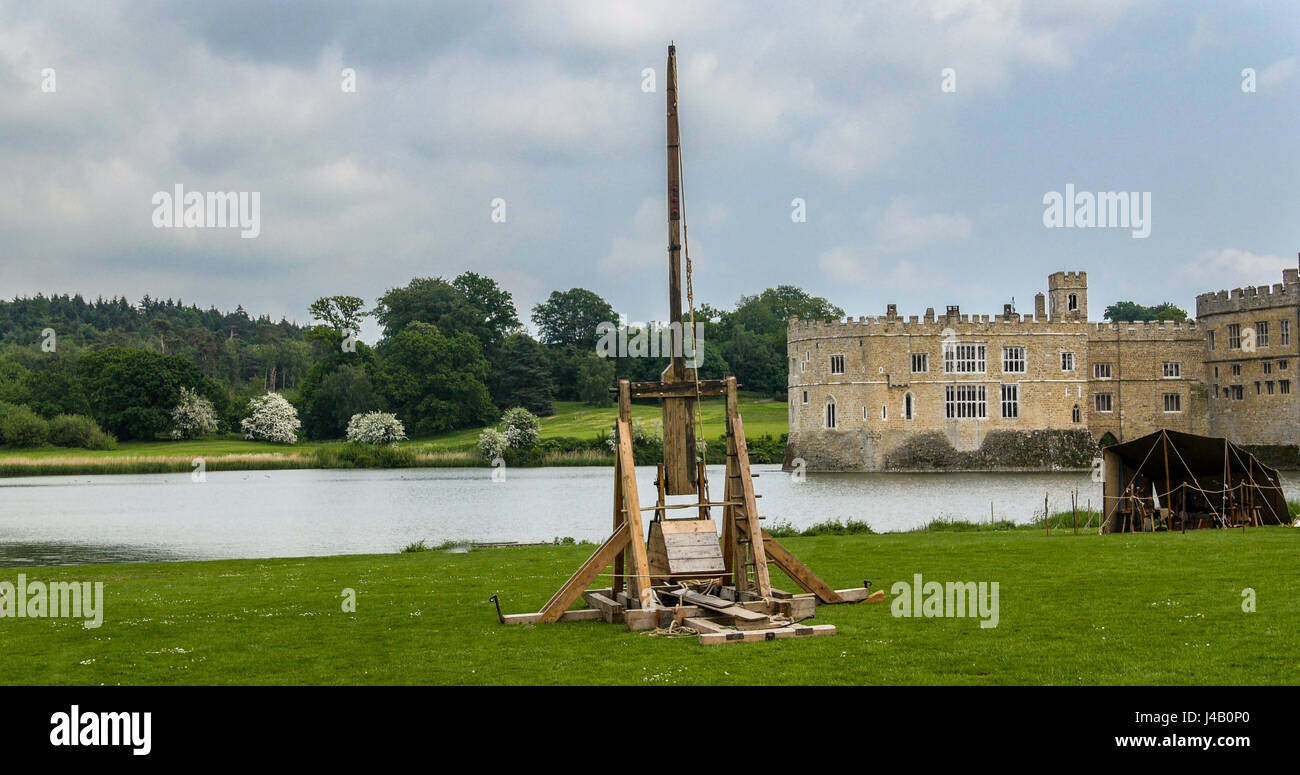 View of a medieval trebuchet with a moated castle in the background Stock Photo