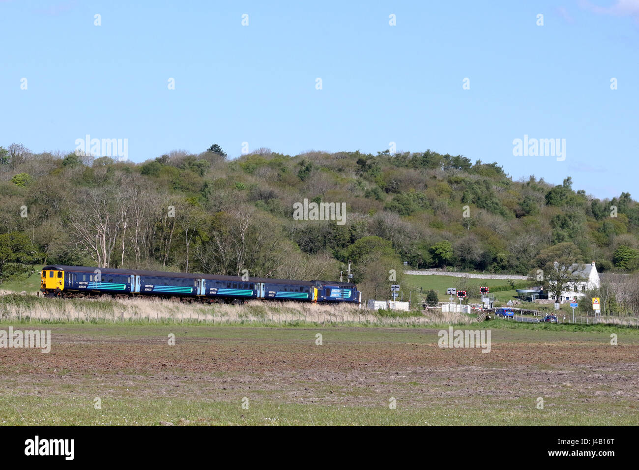 Class 37 diesel with loco hauled passenger train and DVT approaching level crossing on main road to Silverdale, Lancashire Stock Photo