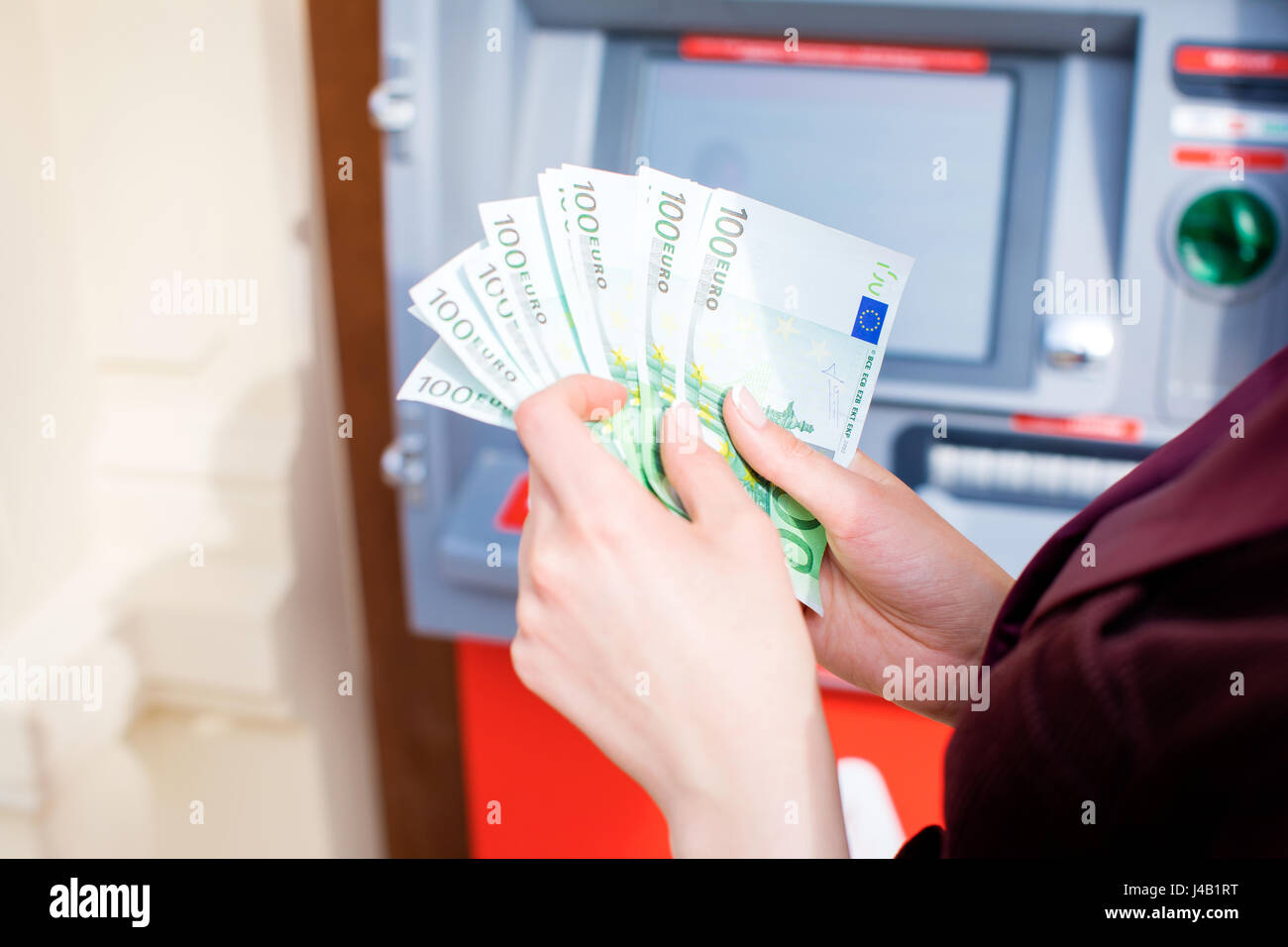 Repayment on credit. Woman hand withdrawing money from outdoor bank ATM Stock Photo