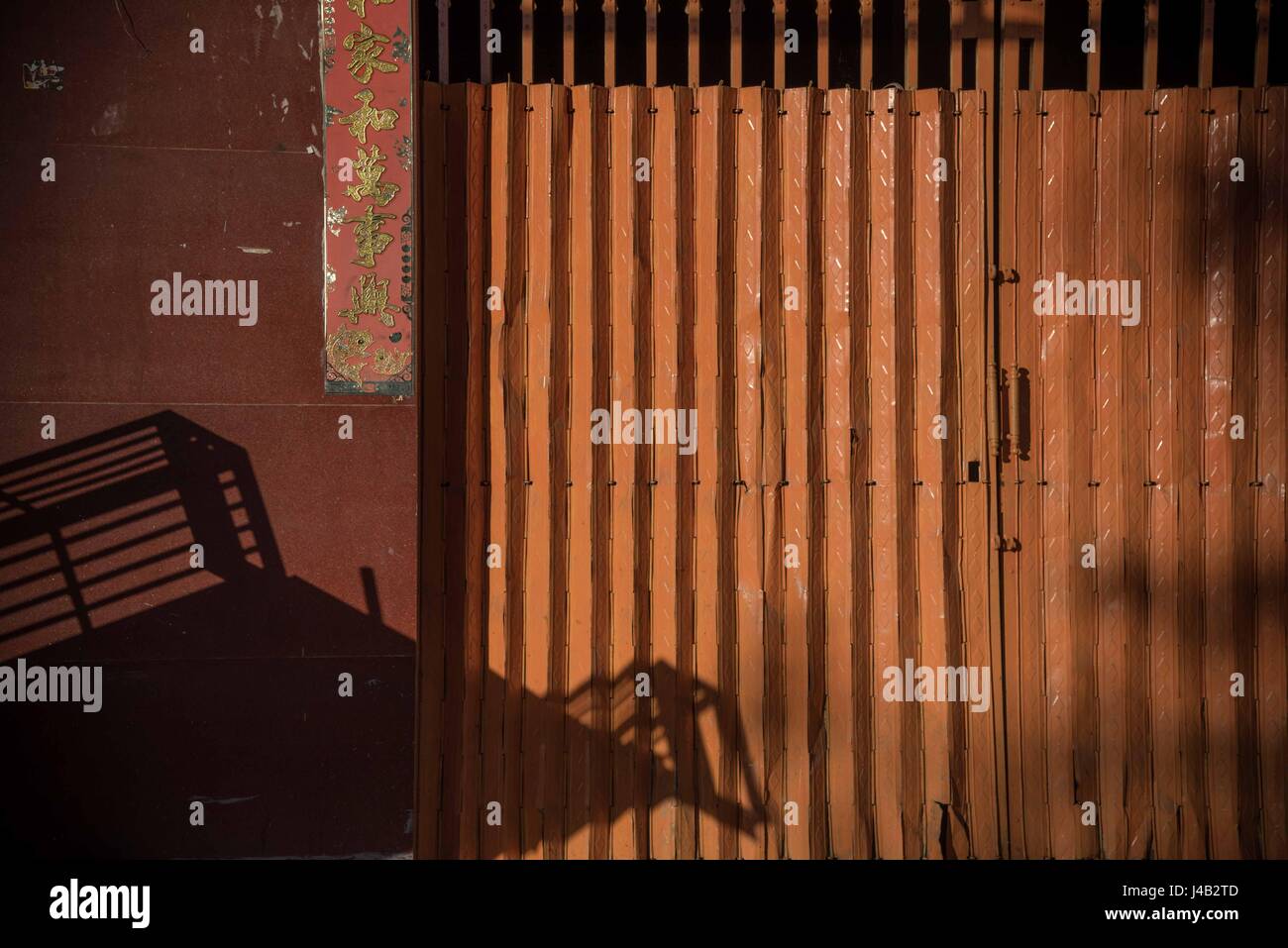 Burnt umber and shadow.  Striking orange gates bathed in warm early morning light, Kampot, Cambodia Stock Photo