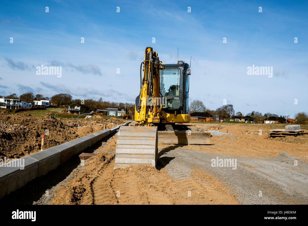 Yellow excavator digging on a construction site on a sunny day with ...